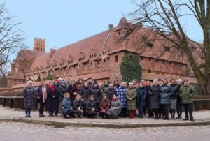 Grupa uczestników spotkania na tle zamku w Malborku